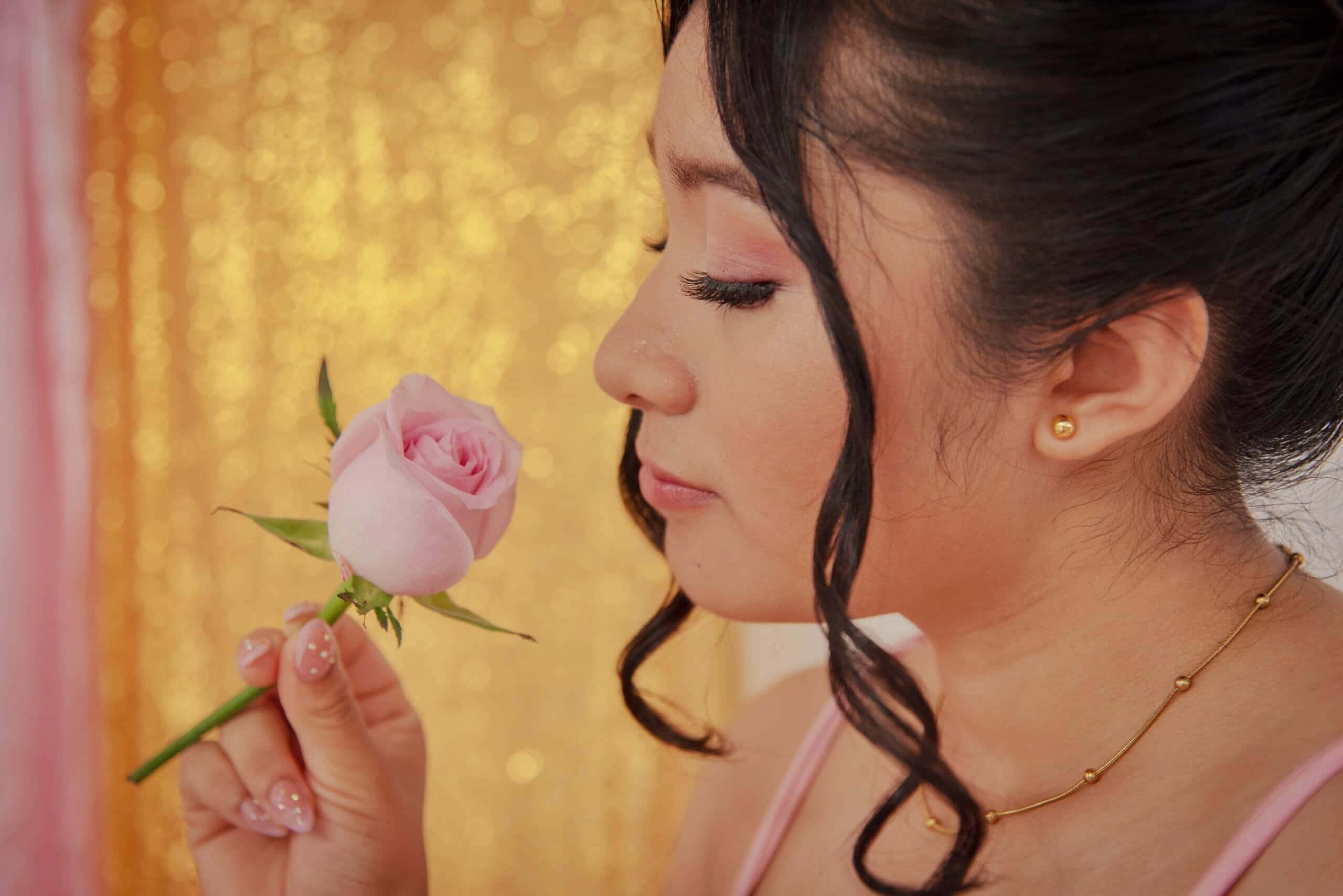 Fotografía de retrato de una mujer disfrutando el olor de una rosa